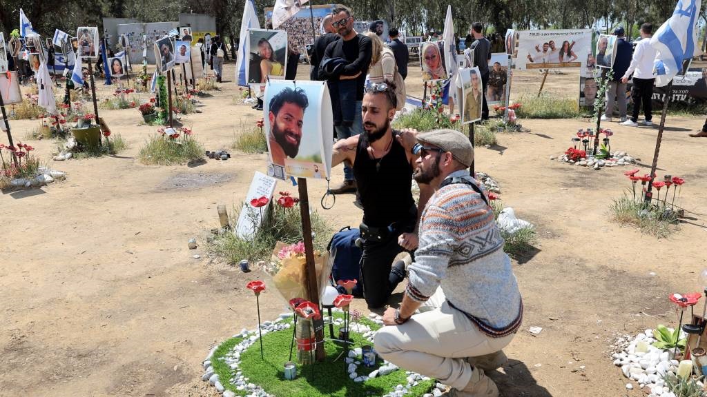 Israelis visit a memorial bearing portraits of peo