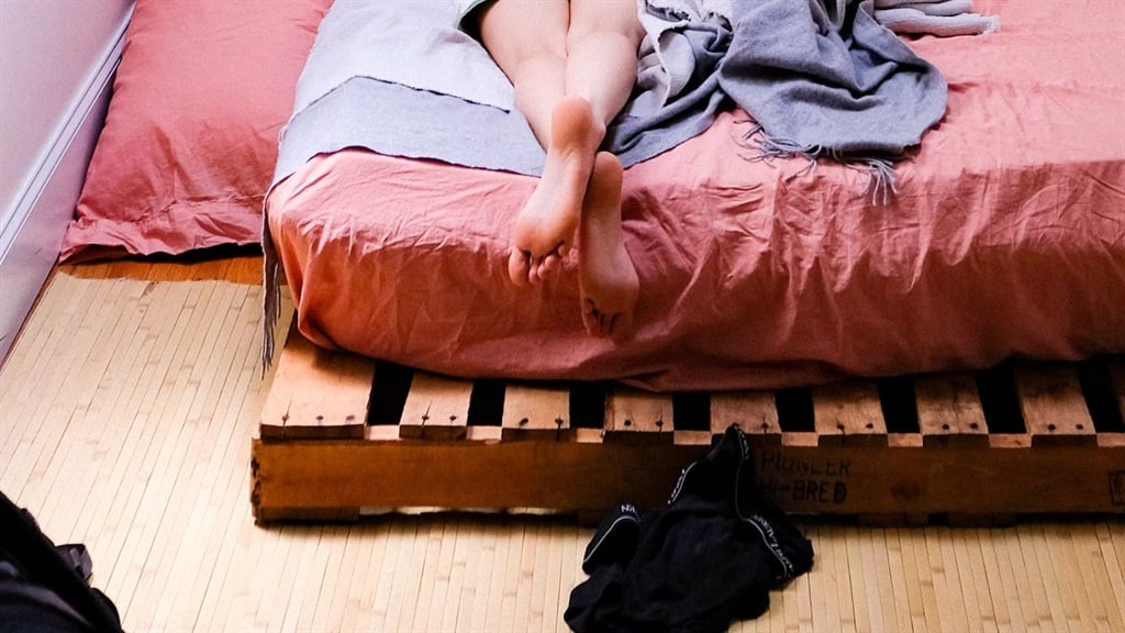 Woman laying on her bed. Image via Unsplash