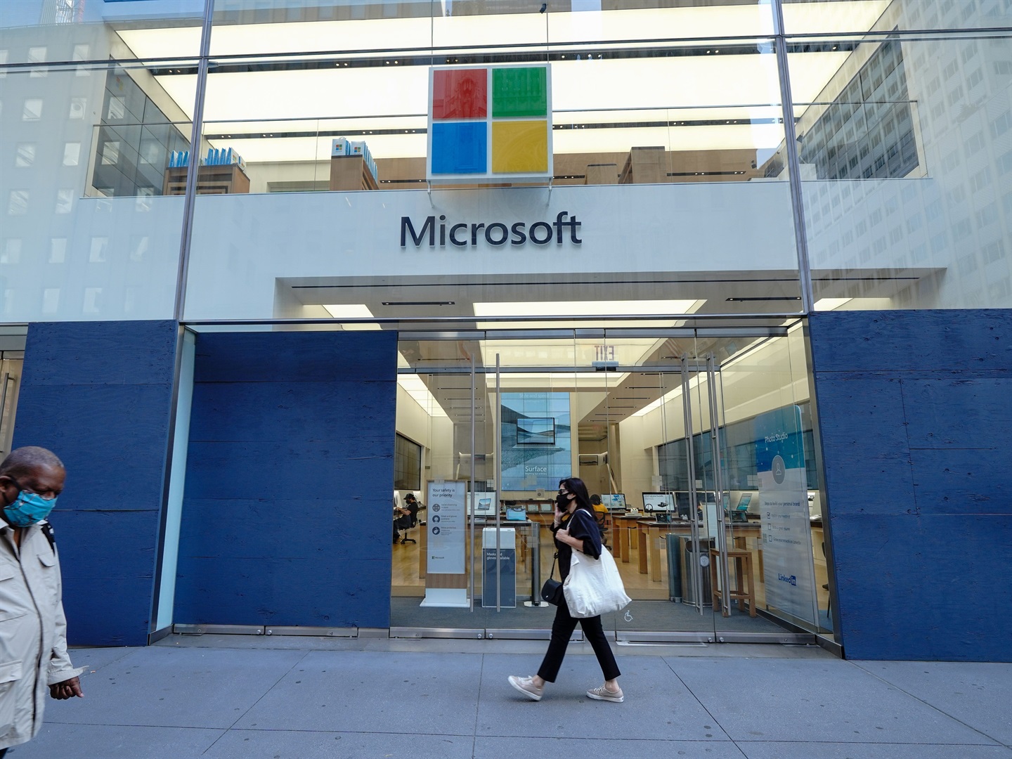 A woman walks past a Microsoft Store on 5th avenue. 