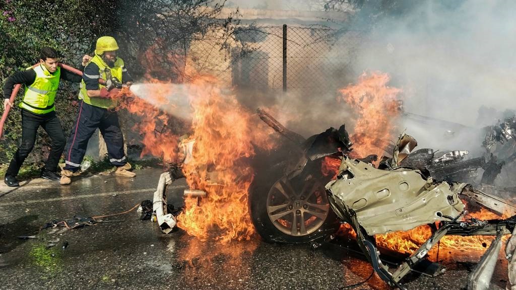 Firefighters douse a burning car after it was hit 