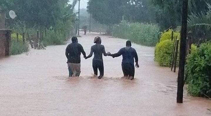 Three people walk through light flooding in Limpopo due to storm Eloise.