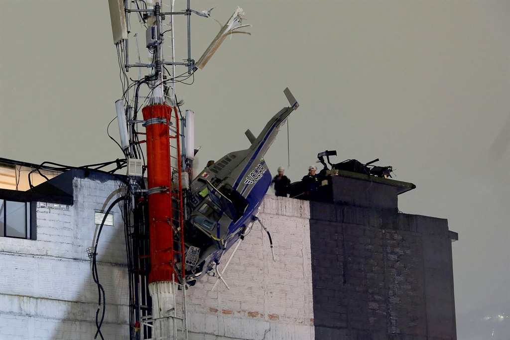 A helicopter hangs from the roof of a building after crashing due to strong winds, according to authorities in Medellin, Colombia, on 26 February 2024.
