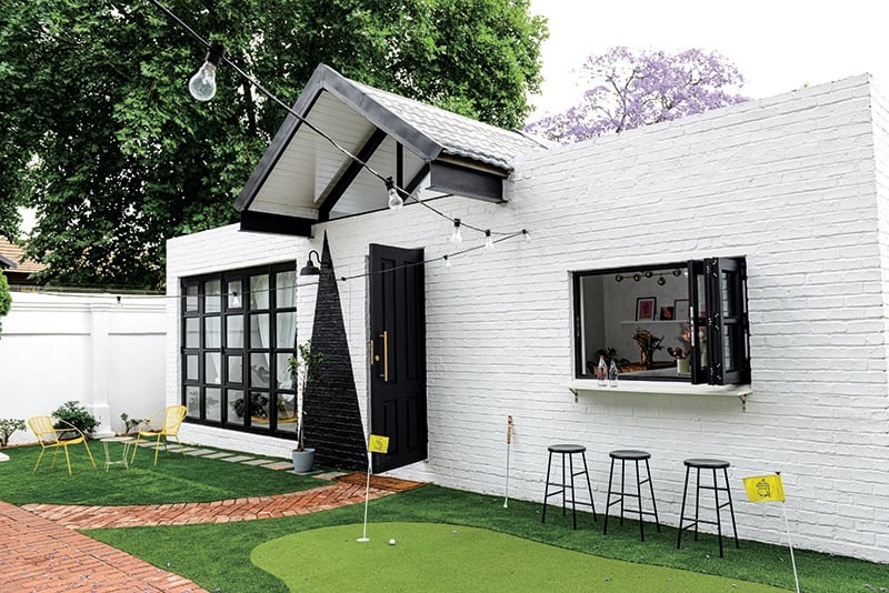 The front of the house has a serving hatch from the kitchen to the outside, where a putting green has been laid out with artificial grass. Black stools from Chair Crazy