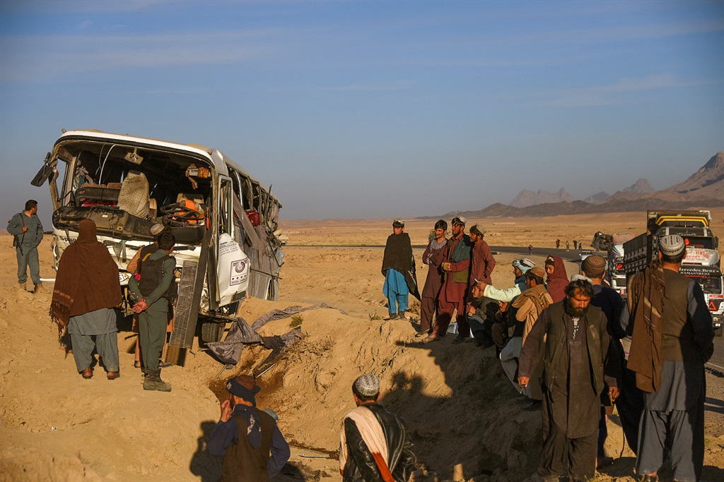 Afghan policemen and bystanders inspect a site after a bus accident along the Kabul-Kandahar highway in December 2018. (Javed Tanveer/AFP)