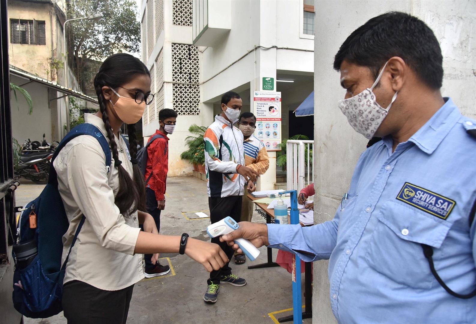 A student gets her body temperature taken in Hyderabad, India.