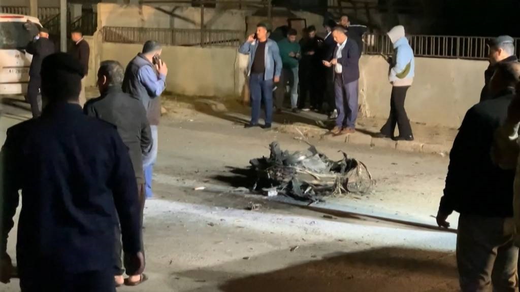 An image grab from AFPTV footage shows Jordanian onlookers and security agents standing around the debris of a missile that the Jordanian forces intercepted over Amman amid an unprecedented Iranian drone and missile attack on Israel. (Ahmad Shoura/AFP)