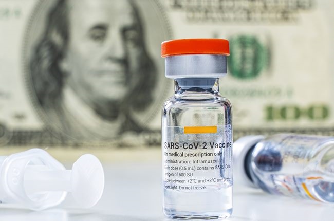 Covid-19 vaccine ampoules and syringe with 100 US dollar banknote on the background