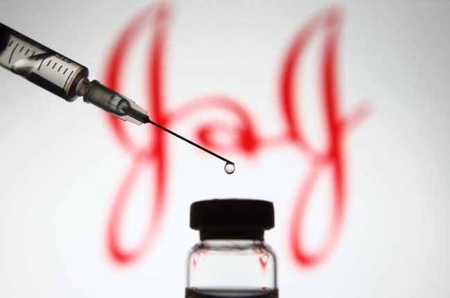 A Johnson & Johnson logo is seen in front of a medical syringe and a vial with coronavirus vaccine.