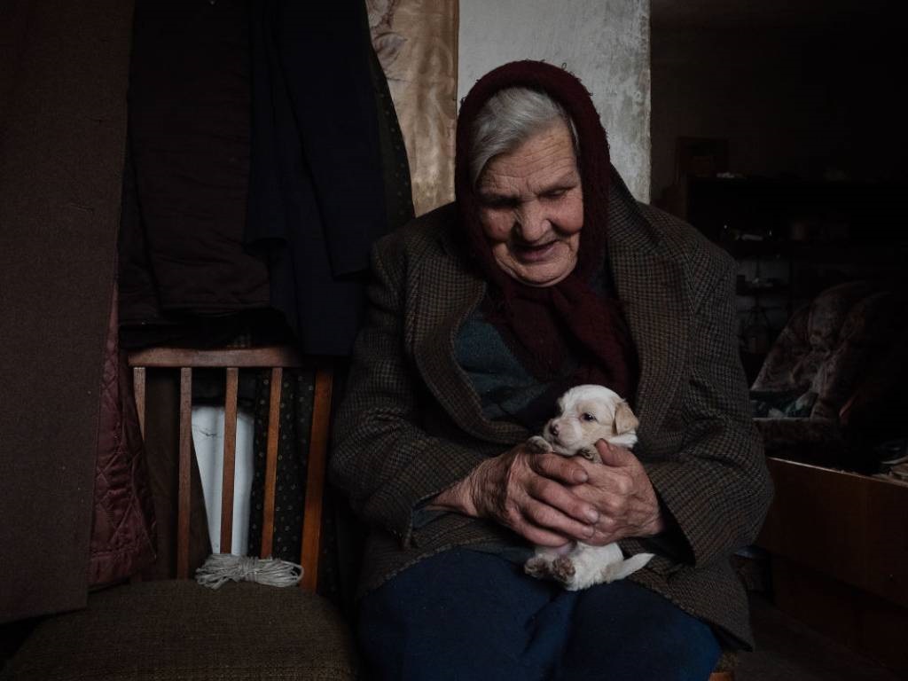 Anna Vasilevna, 84, sits in her home with her dog,