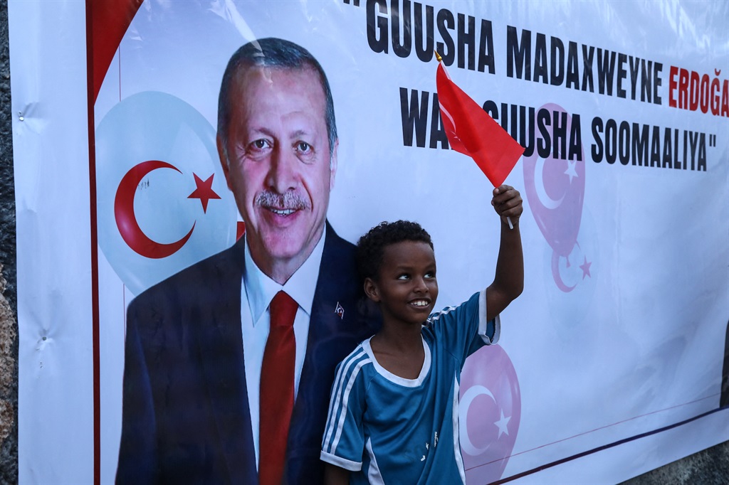 A Somali boy in Mogadishu holds a Turkish flag as people celebrate the victory of Turkish President Recep Tayyip Erdogan in presidential run-off election in May 2023. (Photo by Hassan Ali Elmi / AFP)