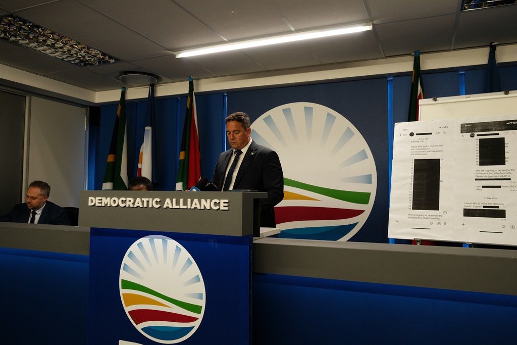 DA leader John Steenhuisen and DA MP Leon Shriver are on the right, holding a printout of a redacted ANC cadre deployment record.