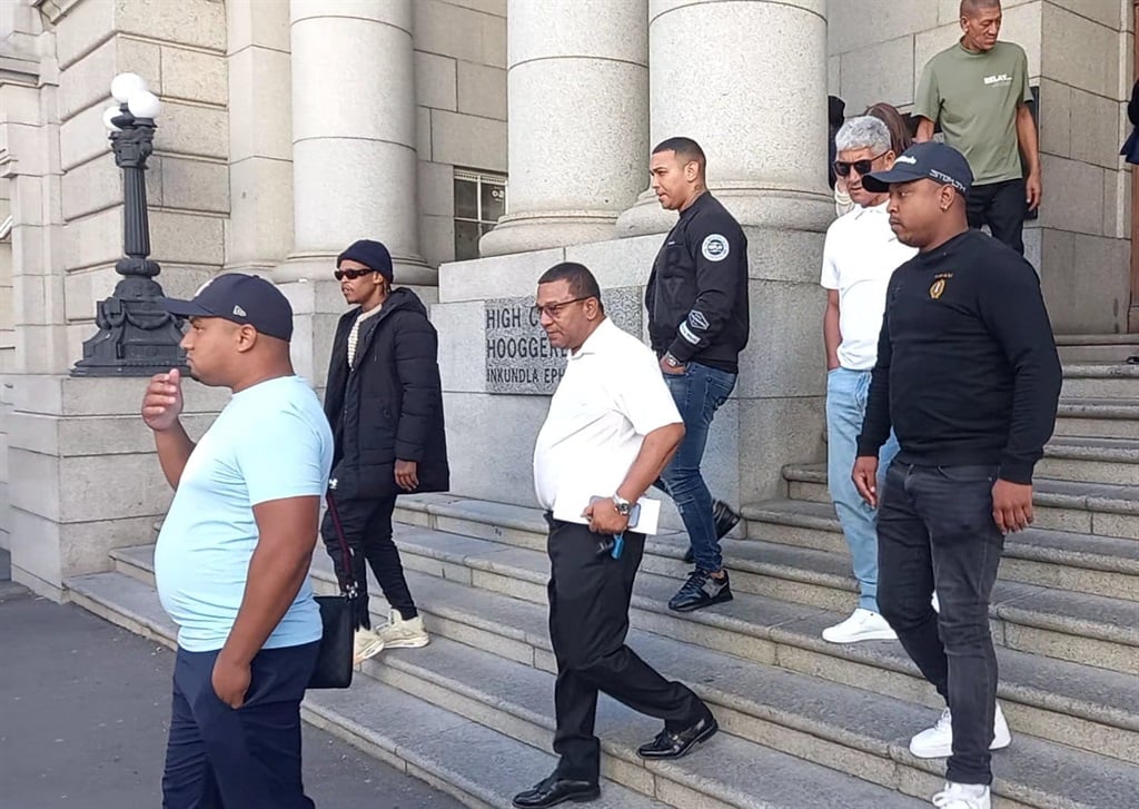 Jerome Booysen (centre) leaves court after hearing he has to wait another year for trial.