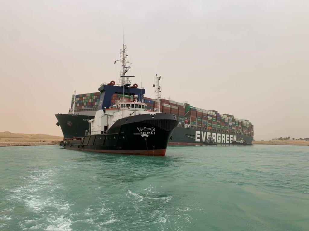 ’n Sleepboot steun die houerskip van die skeepsredery Evergreen, wat Dinsdag in die Suez-kanaal skeefgedraai en vasgesit het. Dit het tot die opeenhoping van minstens 100 ander skepe en tot ’n styging in die olieprys gelei. Foto: Reuters