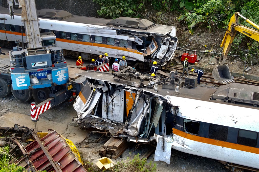 An aerial view shows workers checking damaged carriages at the site of a derailed train accident on the mountains of Hualien, eastern Taiwan on 6 April, 2021.
