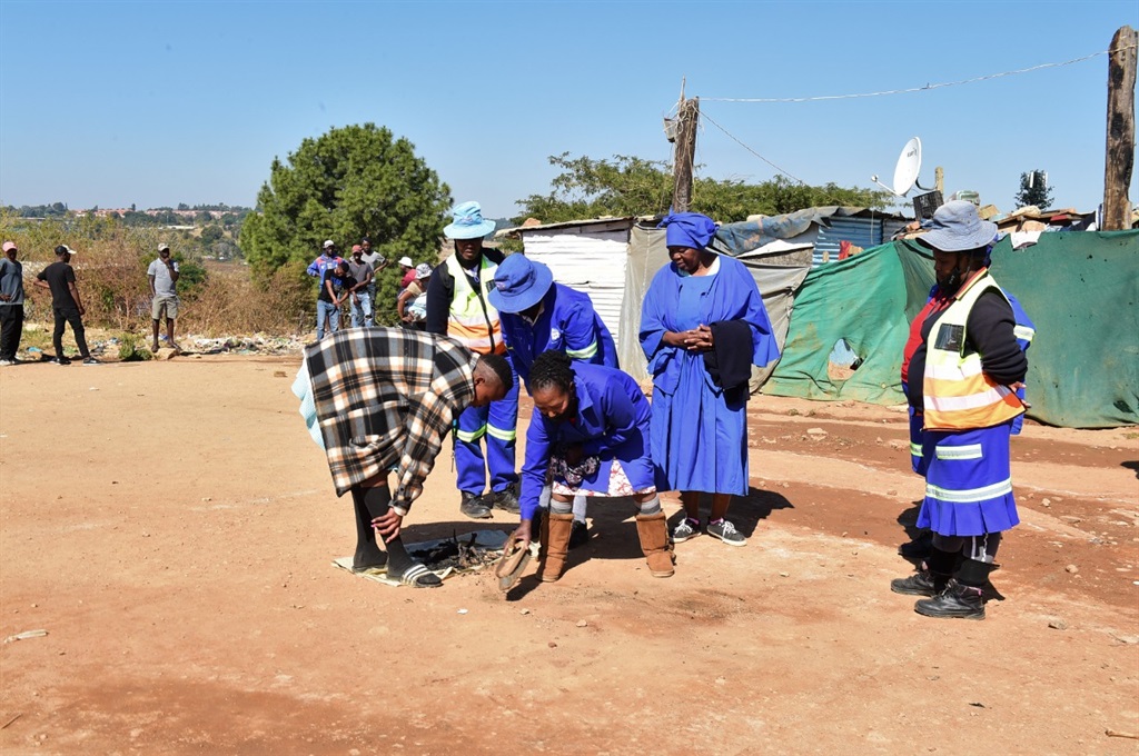 Family members removing ashes of their killed sibling. Photo: Morapedi Mashashe.