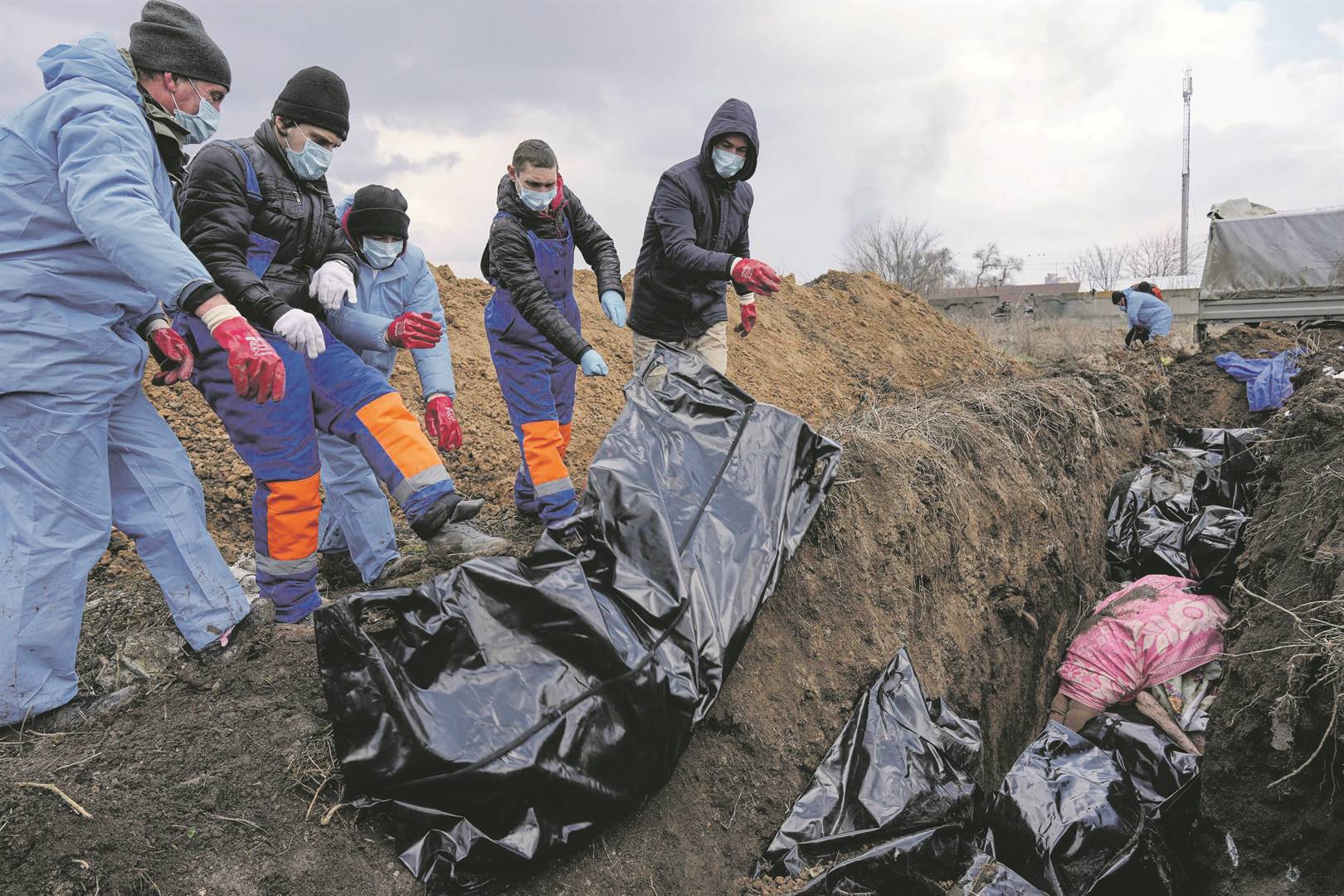 Dead bodies are placed into a mass grave on the outskirts of Mariupol, Ukraine. The war is claiming bodies on both sides . As in the words of Kwame Nkrumah, “When the bull and elephant fight, the grass is trampled down.” Photo: Evgeniy Maloletka / ap photo