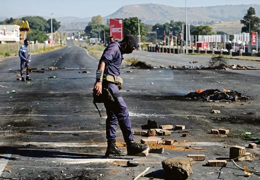 A police officer clears the road in Embalenhle township outside Pietermaritzburg after a service delivery protest by residents. Photo: Tebogo Letsie