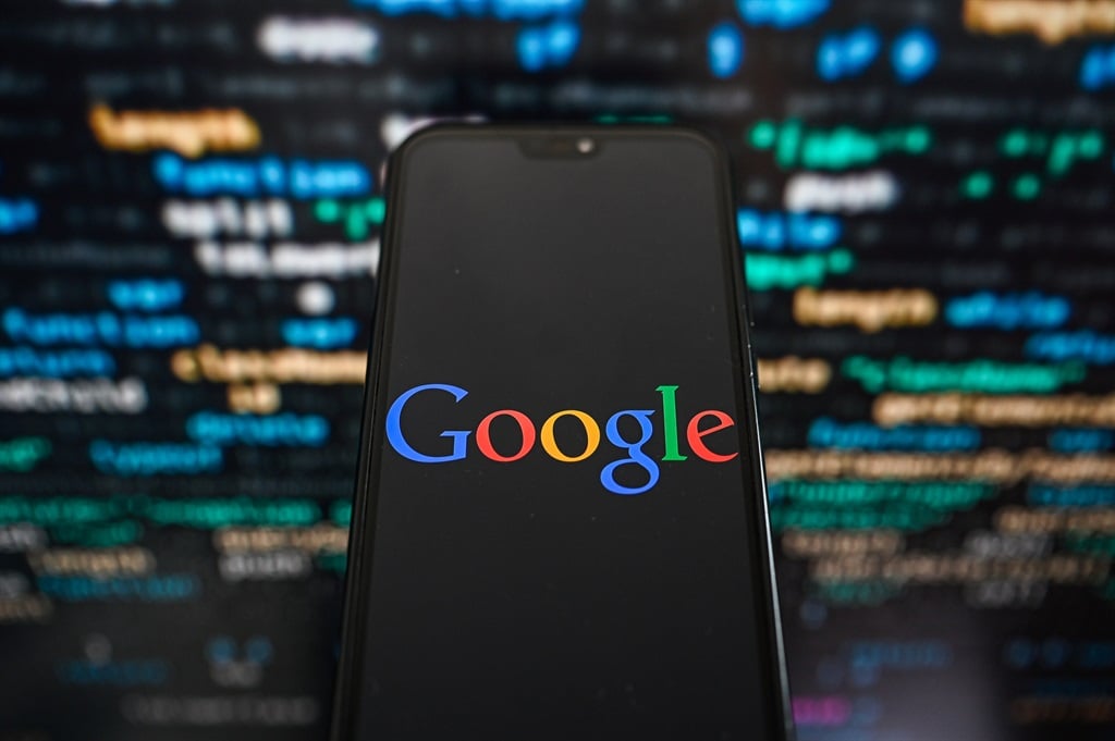 A Google logo is displayed on a smartphone with programming code on the background. (Omar Marques/SOPA Images/LightRocket via Getty Images)