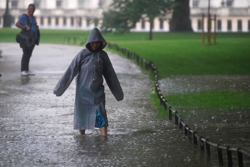 A woman walks through a flooded path in St James's Park in central London. Thunderstorms bringing lightning and torrential rain to the south are set to continue until Monday, forecasters have said. (Photo by Victoria Jones/PA Images via Getty Images)