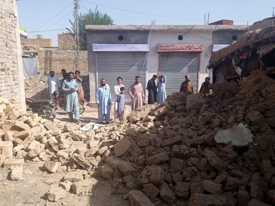Inwoners staan ná die aardbewing by die puin van 'n huis in Harnai in Balochistan, Pakistan.   Foto: Reuters/Naseer Ahmed