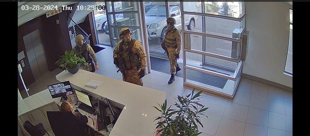 Members of the police's National Intervention Unit stand with rifles at the ready during a raid on a Cape Town law firm. (Supplied)