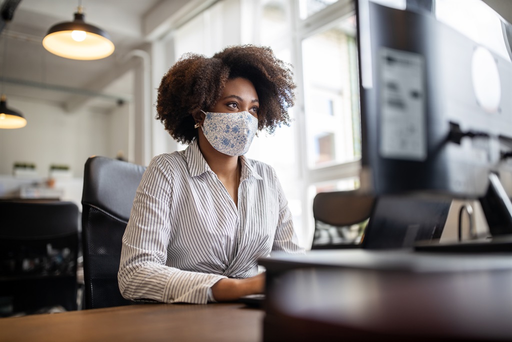 Woman wearing face mask while working at her desk.