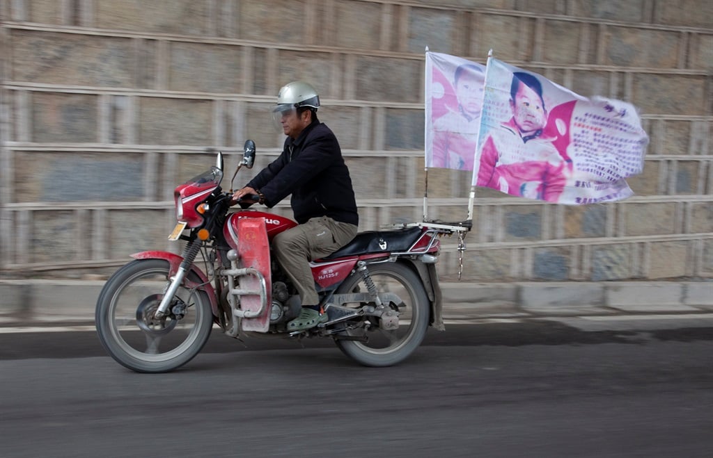 Guo Gangtang, pictured in 2010 on a motorcycle carrying a banner painted with a photo of his missing child at the age of two. (Picture Gallo/ Getty Images)