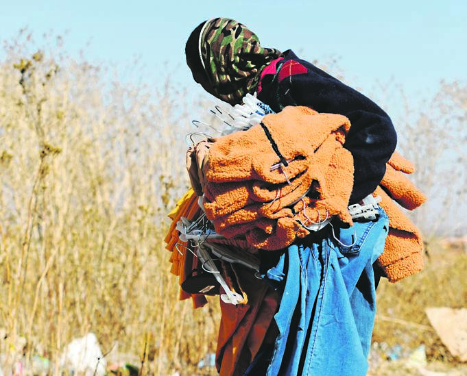 A man carries clothes he looted fromJ abulani Mall in Soweto. Photo: Tebogo Letsie/City Press
