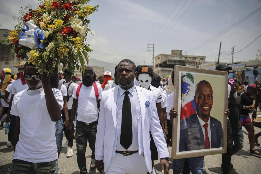 Jimmy Cherizier, alias Barbecue (langs die foto), ’n voormalige polisielid wat aan die hoof staan van ’n bende-koalisie bekend as G9 Family and Allies, lei Maandag ’n optog om geregtigheid vir Moïse te eis in Laer Delmas, ’n distrik in Port-au-Prince.  Foto: AP