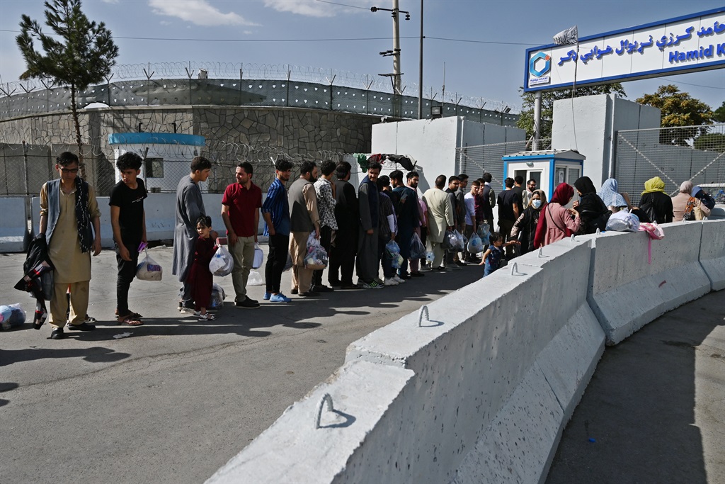 Afghans, hoping to leave Afghanistan, queue at the main entrance gate of Kabul airport in Kabul on 28 AugusT 2021, following the Taliban stunning military takeover of Afghanistan.