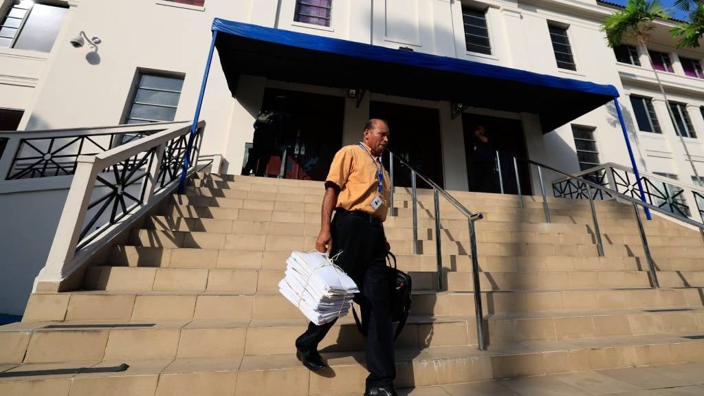 A man carries documents outside the courthouse whe