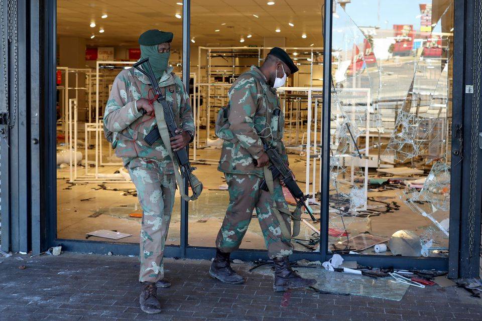 Soldate loop vroeër verby ’n geplunderde winkel in Soweto.  Foto: Reuters