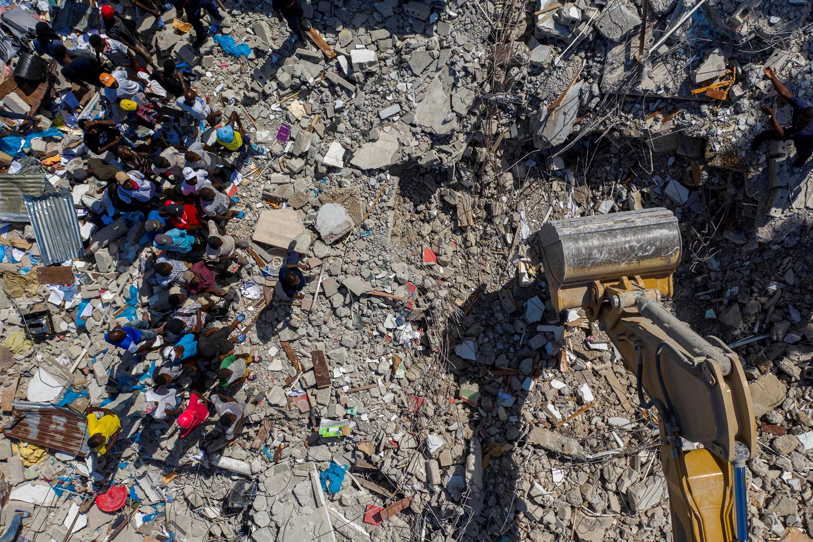 Mense drom saam en kyk na die skade wat aan die kusdorp Les Cayes in Haïti aangerig is. Foto: Reuters