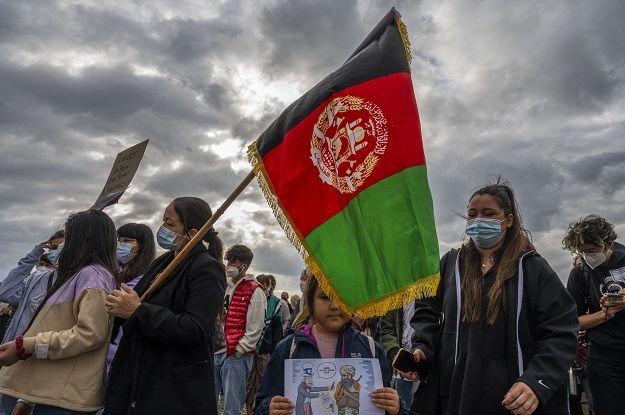 A woman waves an Afghan flag as she demonstrates i