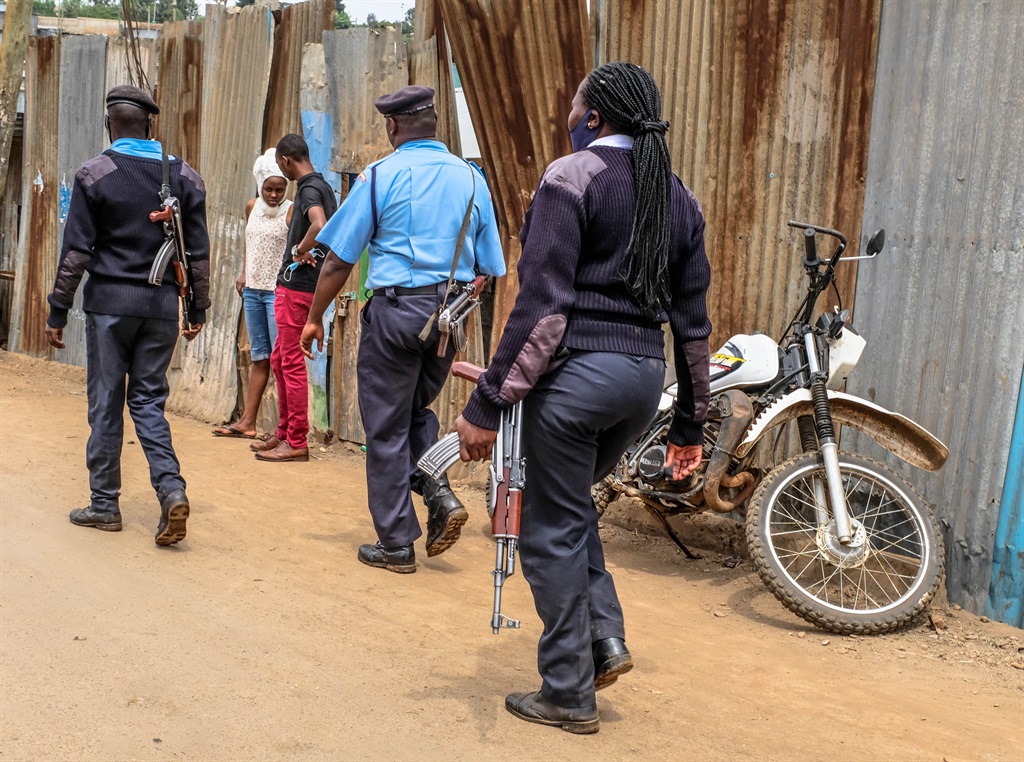 NAIROBI, KENYA - 2020/07/16: Police officers walk past a couple on the street during the Coronavirus Pandemic.