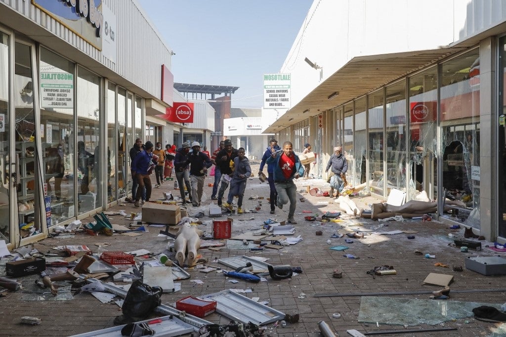 People flee from police as they carry goods while looting and vandalising the Lotsoho Mall in Katlehong township, East of Johannesburg.