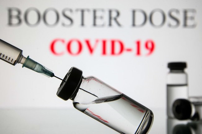 UKRAINE - 2021/09/07: In this photo illustration a medical syringe and vials are seen displayed in front of the Booster dose and Covid-19  text. (Photo Illustration by Pavlo Gonchar/SOPA Images/LightRocket via Getty Images)