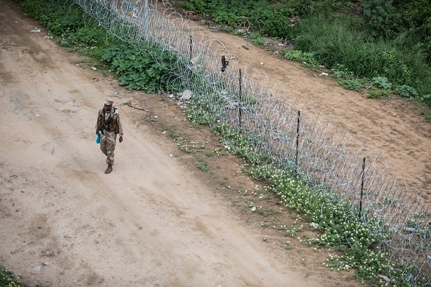 A SANDF soldier walks along the border fence that separates South Africa and Zimbabwe, near the Beitbridge border post. 