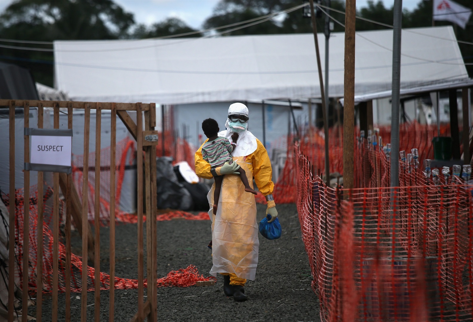 A Doctors Without Borders (MSF) health worker in protective clothing carries a child suspected of having Ebola.