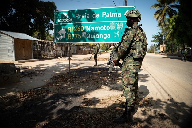 A Rwandan soldier walks in front of a burned truck