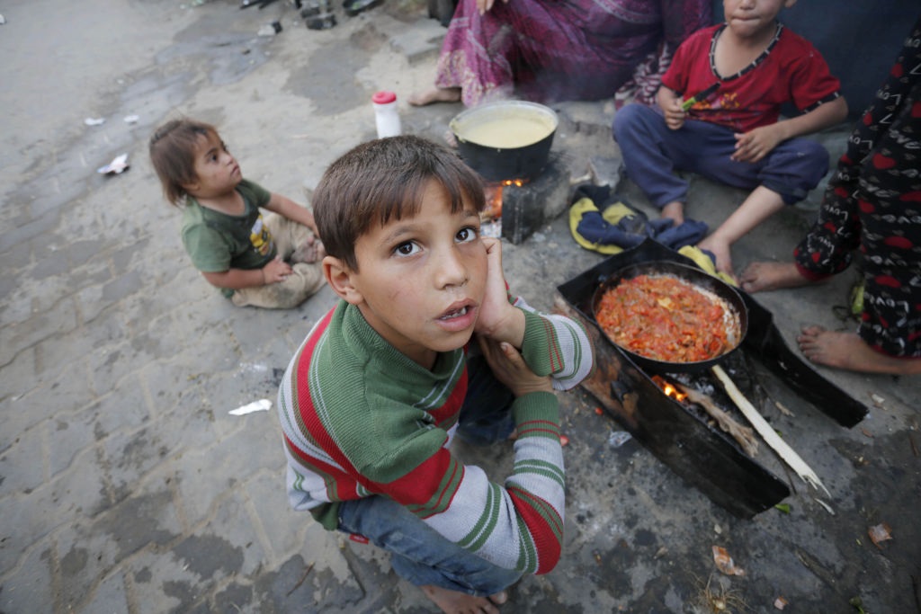 Palestinian children wait next to a fire as people prepare food for breaking their fast during the holy month of Ramadan amid dramatic starvation and hunger due to Israeli blockade in the besieged Gaza Strip. (Ashraf Amra/Anadolu via Getty Images)