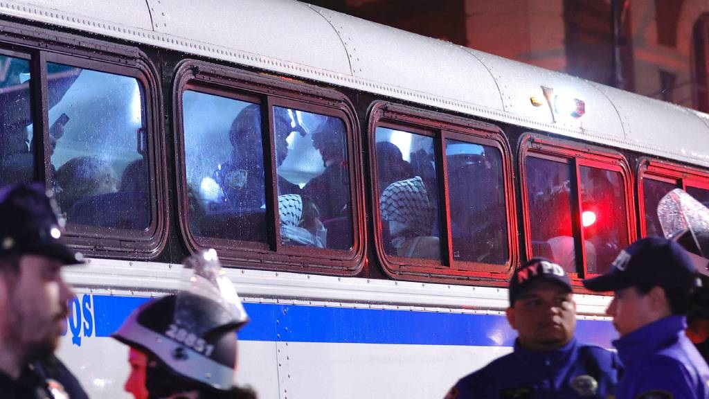 افسران پلیس نیویورک دانش آموزان دستگیر شده را با اتوبوس منتقل می کنند