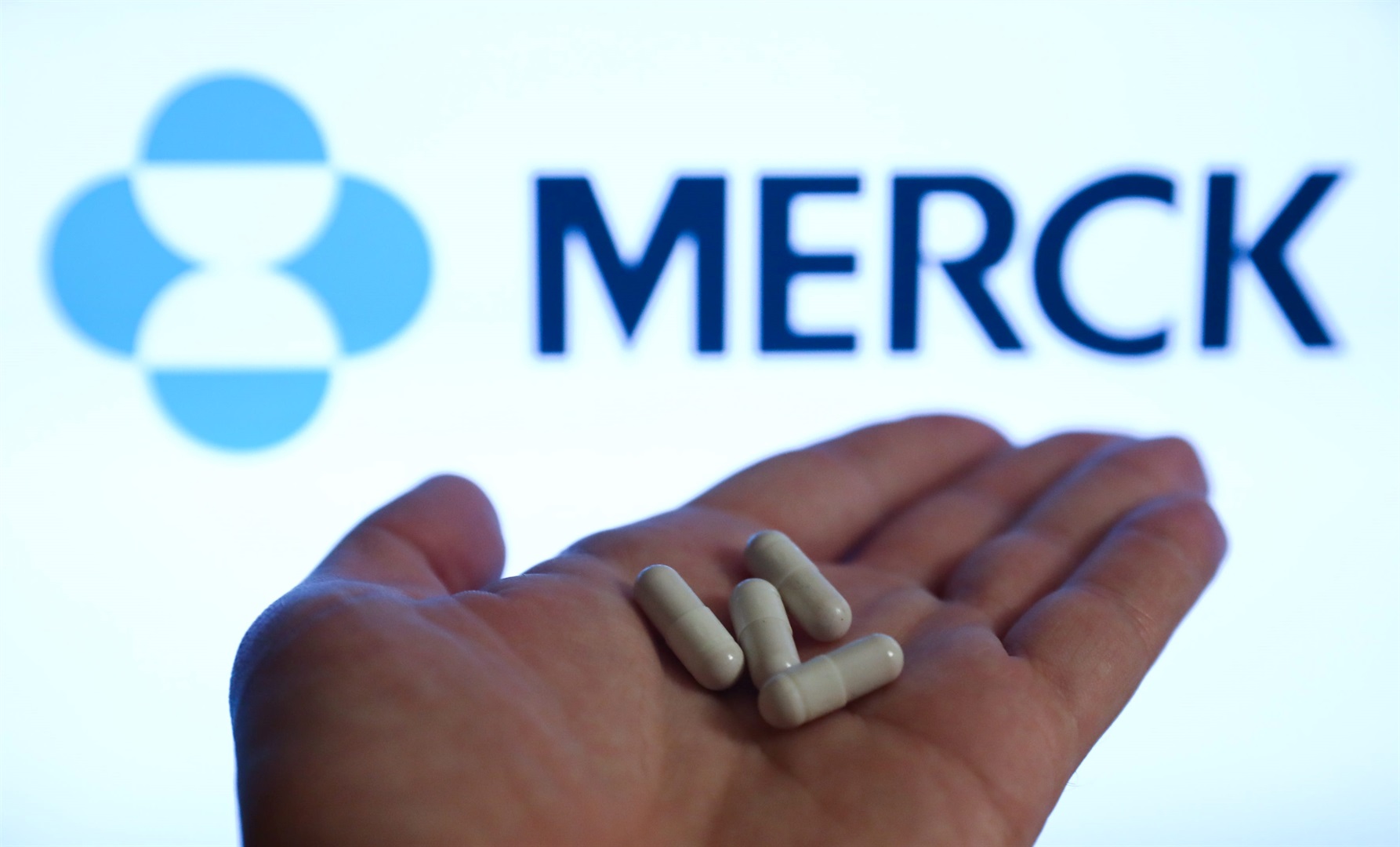 Pills seen with the Merck logo in the background.
