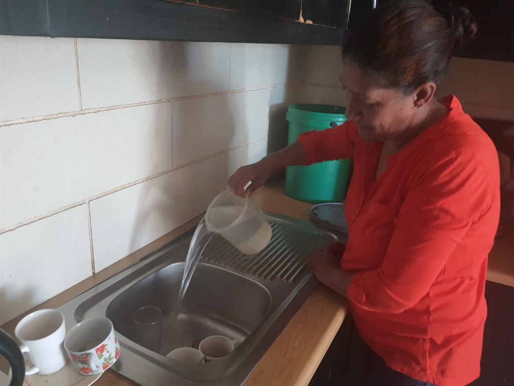 Claudine Felix pours water into the sink to wash t