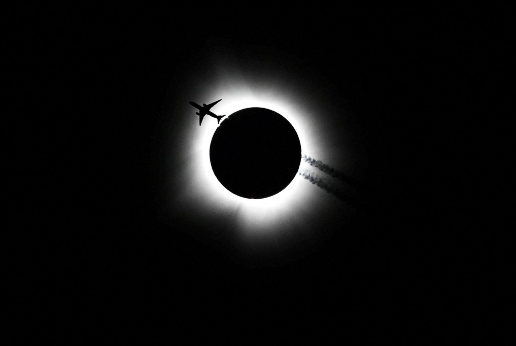 An airplane passes near the total solar eclipse du