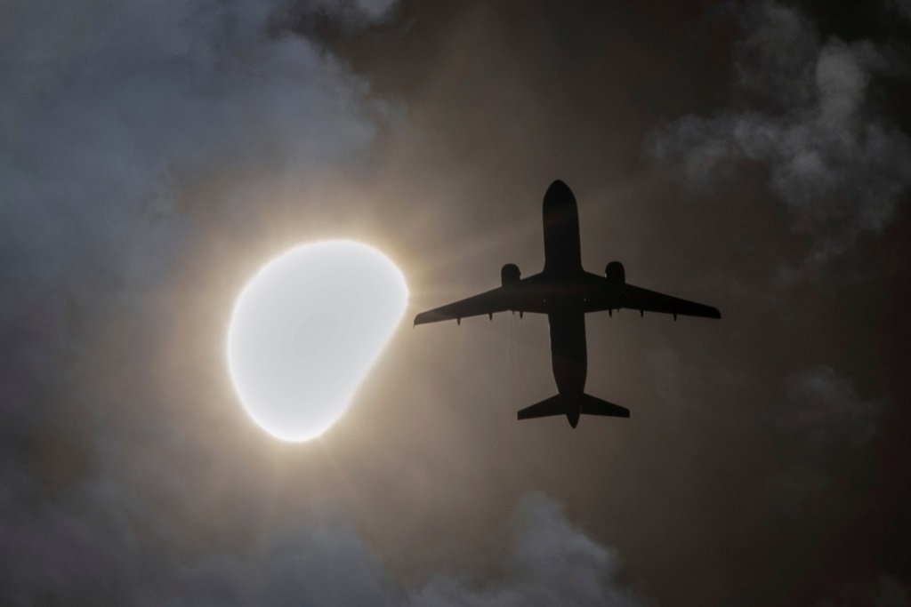 An airplane passes during a partial solar eclipse 