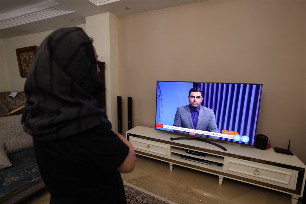 An Iranian woman watches an Iranian news TV channel covering the news of Iran's attack on Israel, on 14 April 2024. (ATTA KENARE / AFP)