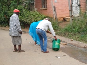 Residents cleaning the blood on the road in Nhlungwane, where two bodies were found. 
