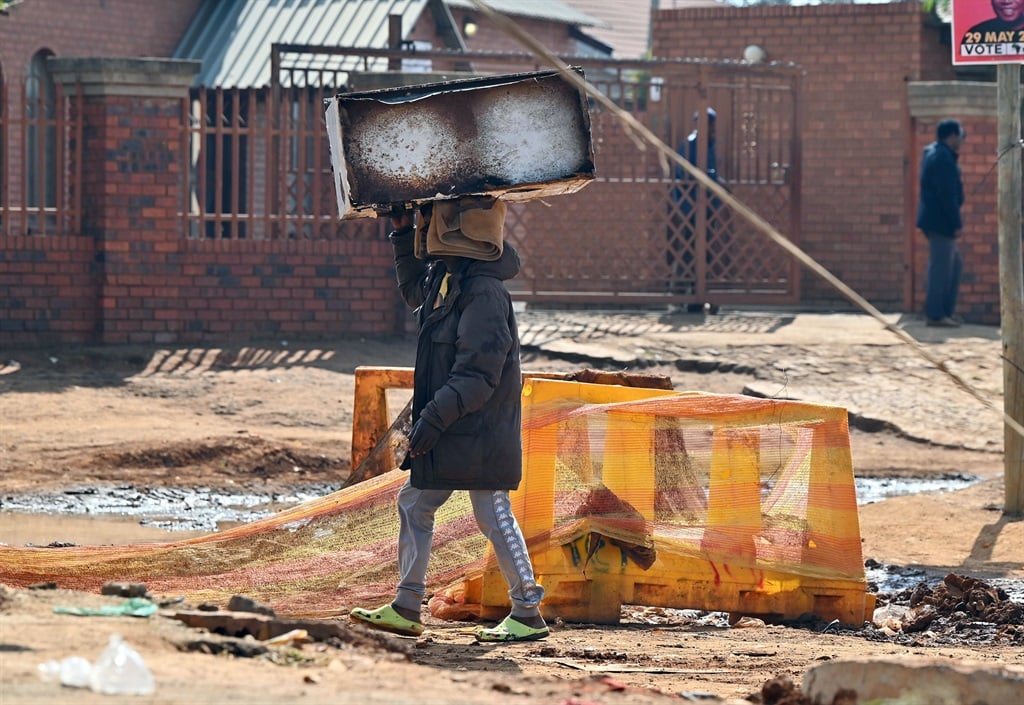 A man carrying an old cupboard for recycling. Bekk