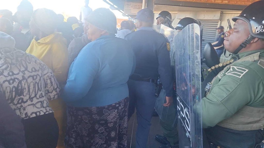 Authorities try to hold back community members outside a Shoprite store in Ratanda, Heidelberg, where a man died after being locked inside a cold storage room overnight. (Alex Patrick, News24)